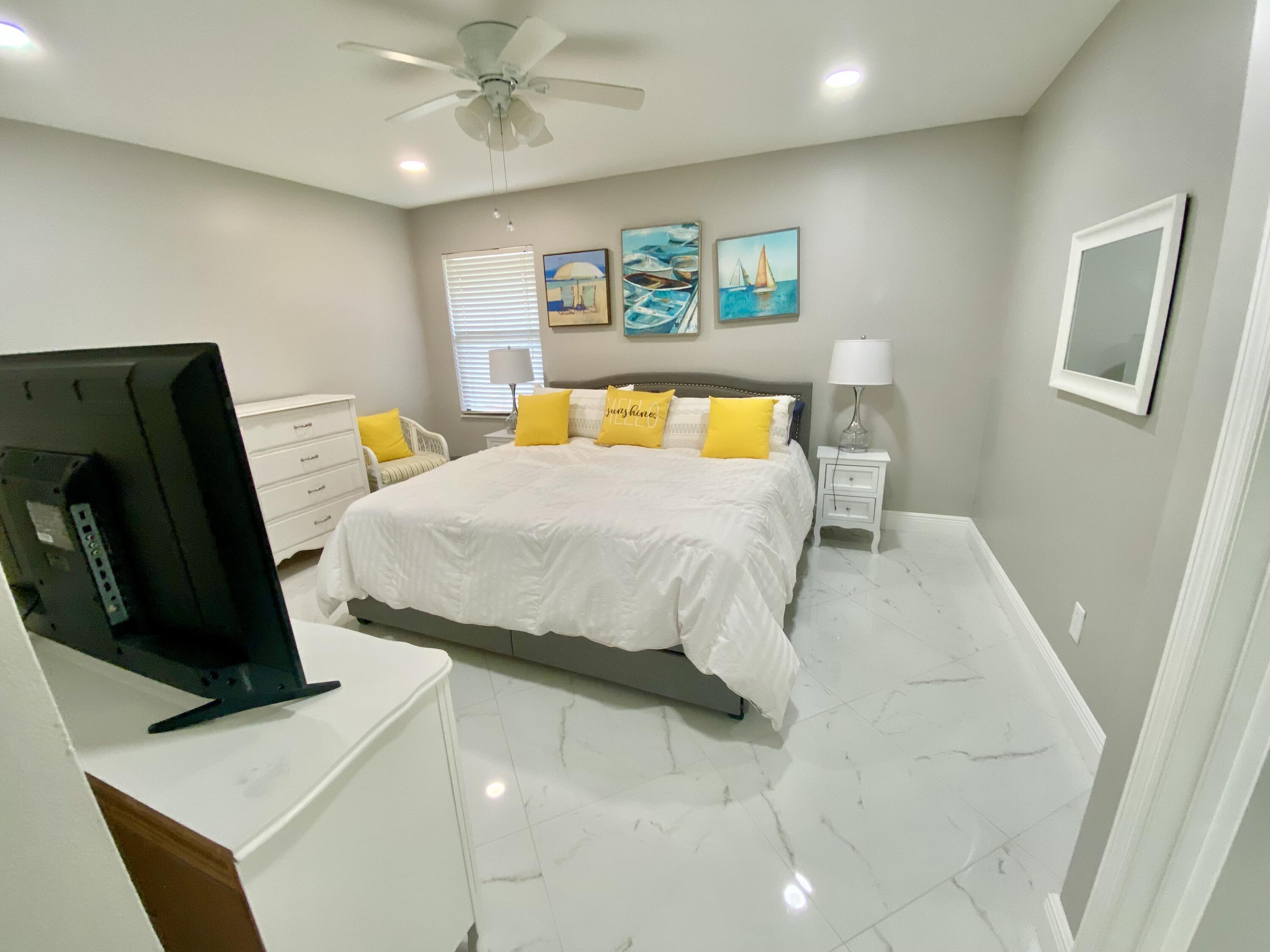 1127 East Seminole Avenue, Unit 13D Jupiter, FL 33477 - Photo 7 of 20 a bedroom with a bed a couch and paintings on the wall