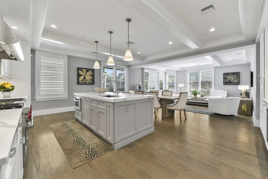 a large white kitchen with a large window a counter space a sink stainless steel appliances and white cabinets