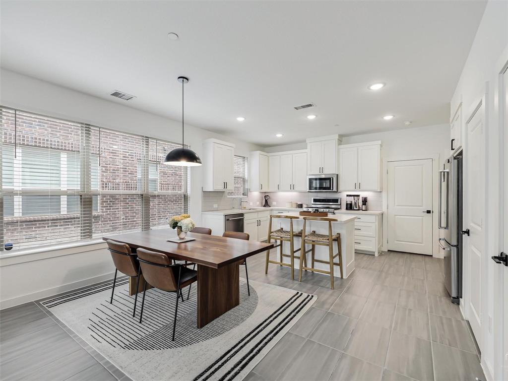 5912 Ridgeline Drive McKinney, TX 75070 - Photo 5 of 22 a kitchen with stainless steel appliances kitchen island granite countertop a table chairs stove and white cabinets