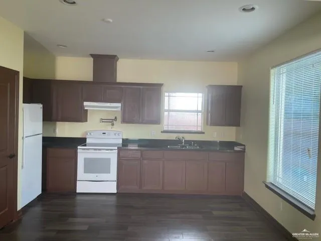 a kitchen with stainless steel appliances a sink stove and wooden floor