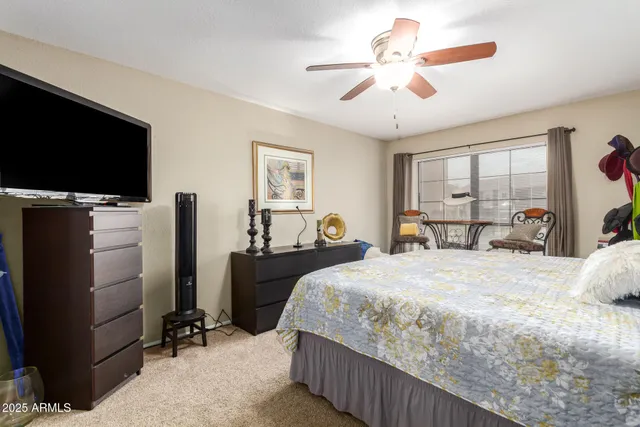 a bedroom with bed tv and a window