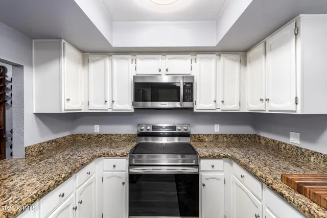a kitchen with granite countertop white cabinets and stainless steel appliances