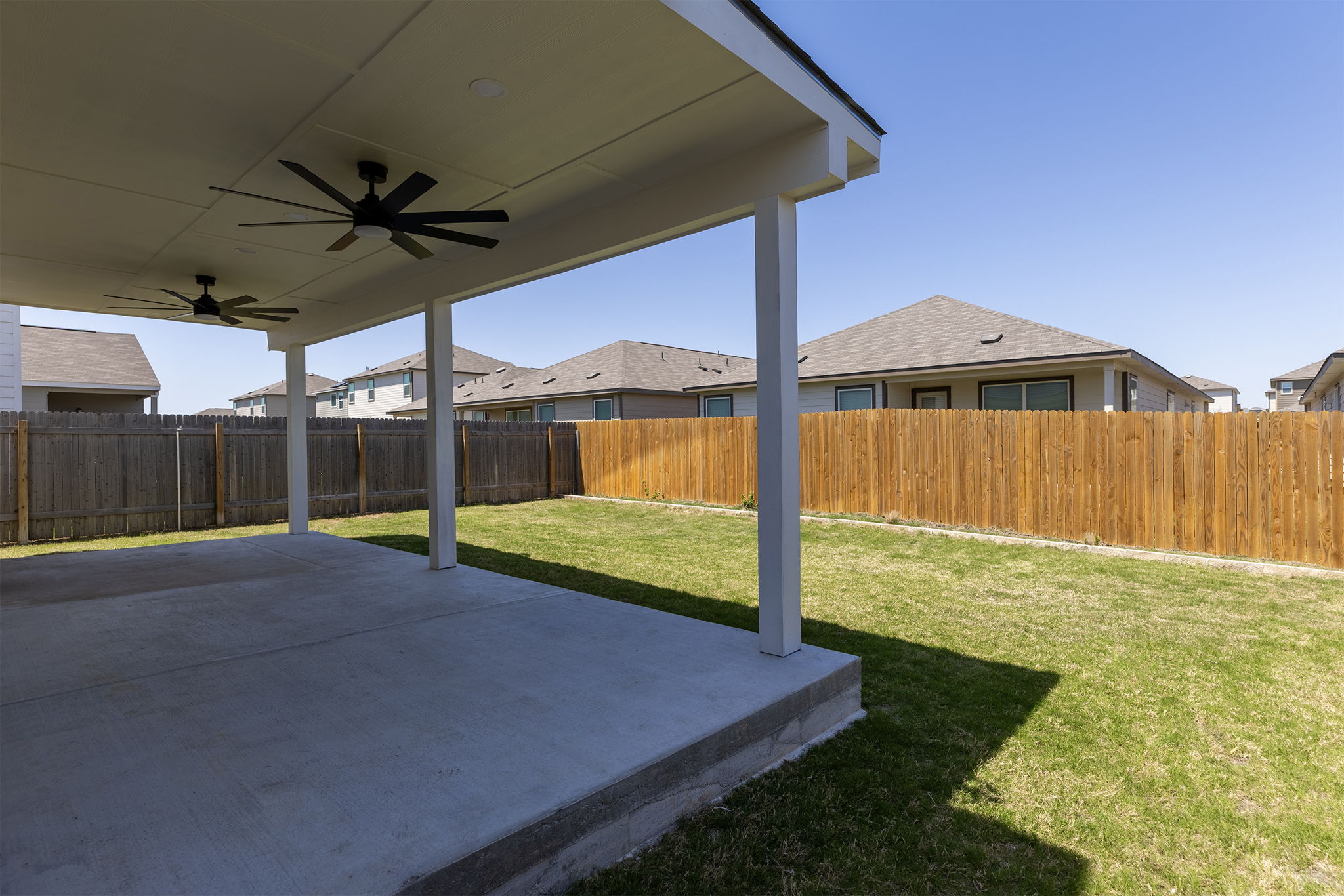 409 Line Of Fire Way Jarrell, TX 76537 - Photo 28 of 30 Expansive covered patio featuring two ceiling fans with integrated lighting, concrete flooring, exterior lighting, and direct access to the fenced backyard.