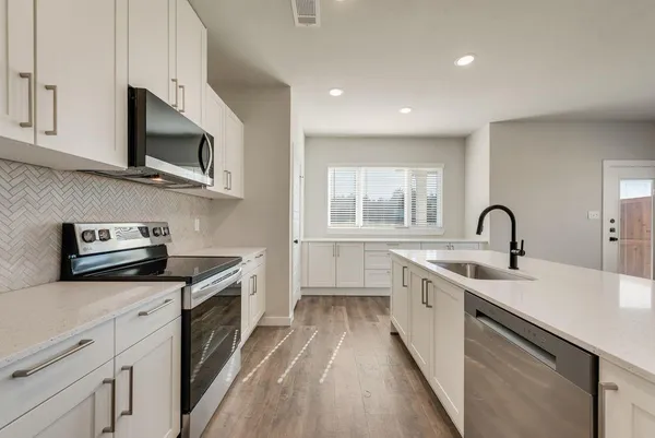 a kitchen with stainless steel appliances granite countertop a sink and a stove top oven