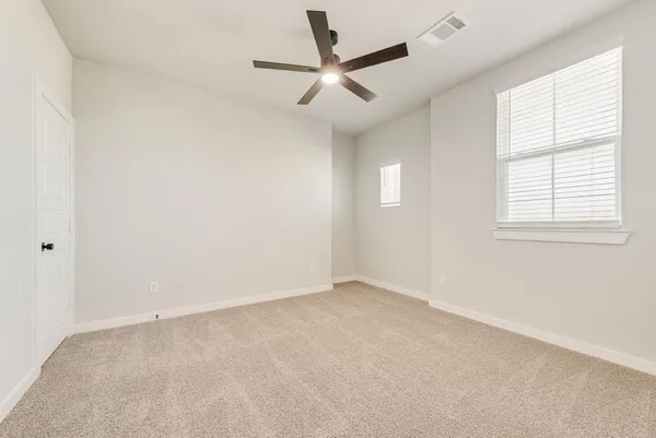 an empty room with a ceiling fan and windows