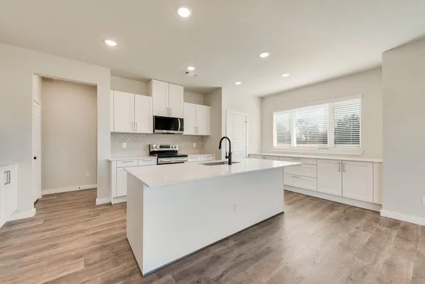 a large white kitchen with sink a microwave and refrigerator