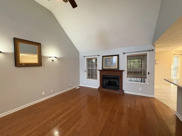 a view of an empty room with wooden floor fireplace and a window