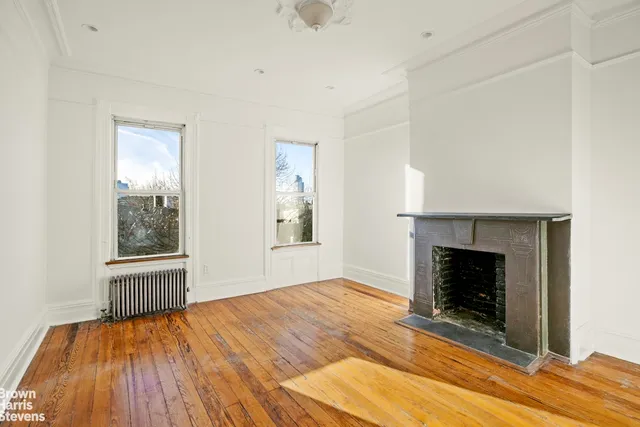 an empty room with wooden floor fireplace and windows