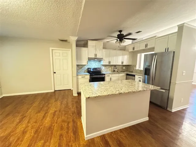 a kitchen with stainless steel appliances a dining table chairs and a refrigerator