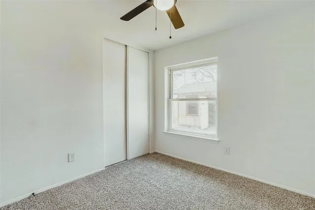 an empty room with a window and ceiling fan