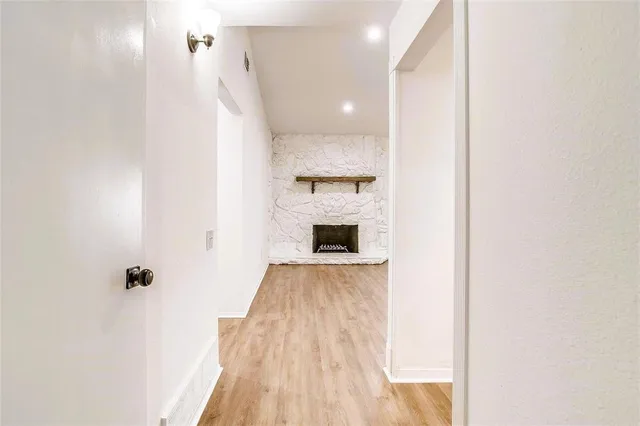 a view of a hallway with wooden floor and a bathroom