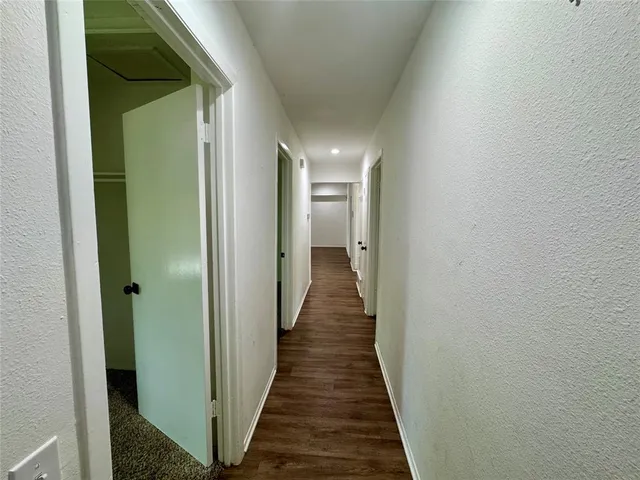 a view of a hallway with wooden floor and a bathroom