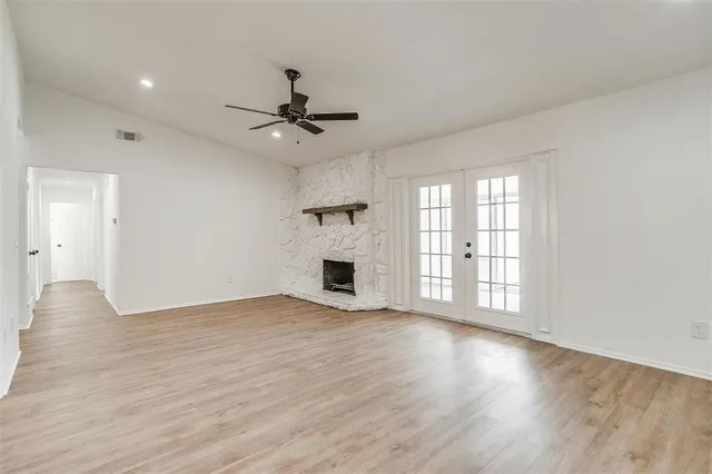 a view of an empty room with a fireplace and wooden floor