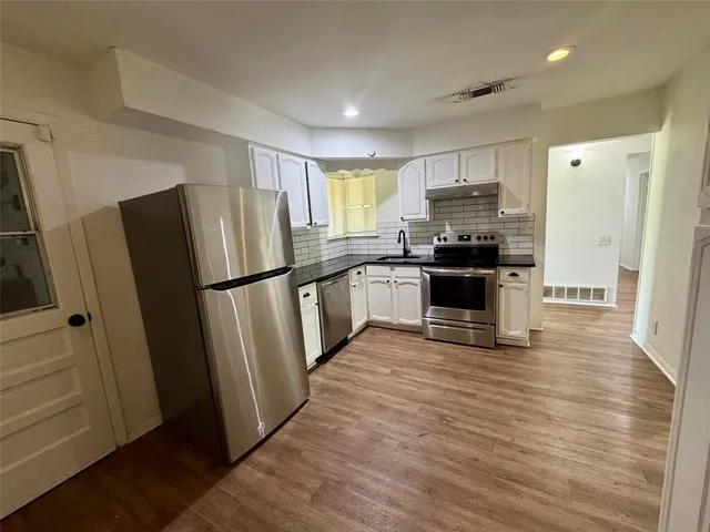 a kitchen with stainless steel appliances a refrigerator and wooden floor