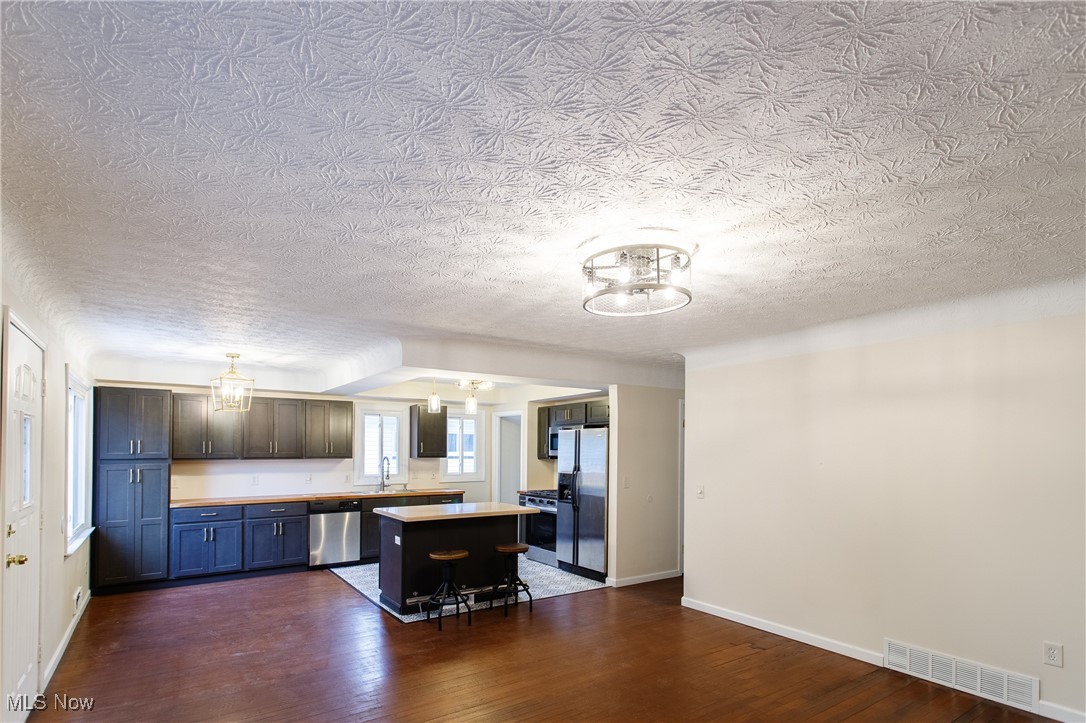 31827 Glenhurst Road Willowick, OH 44095 - Photo 14 of 44 Kitchen with a chandelier, appliances with stainless steel finishes, a center island, dark wood finished floors, and a textured ceiling