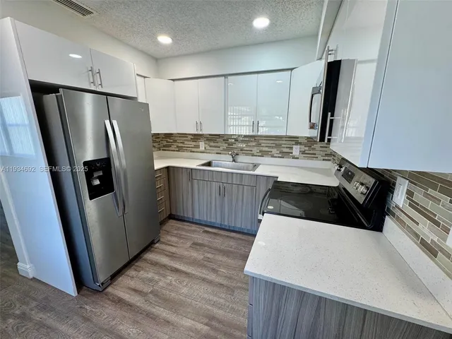 a kitchen with stainless steel appliances granite countertop a refrigerator a sink and a stove