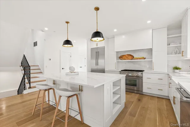 a kitchen with kitchen island granite countertop a sink a stove a dining table and chairs