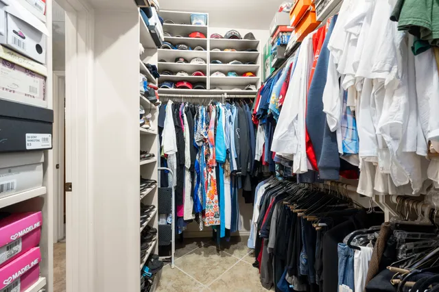 a view of walk in closet with clothes and shoes