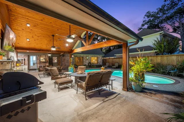 a view of a patio with a table and chairs under an umbrella with a barbeque