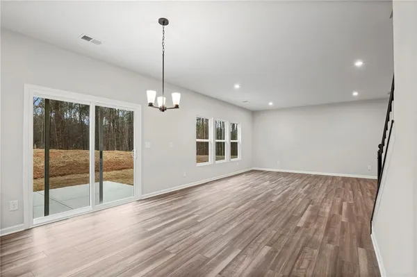a view of a room with wooden floor chandelier and windows