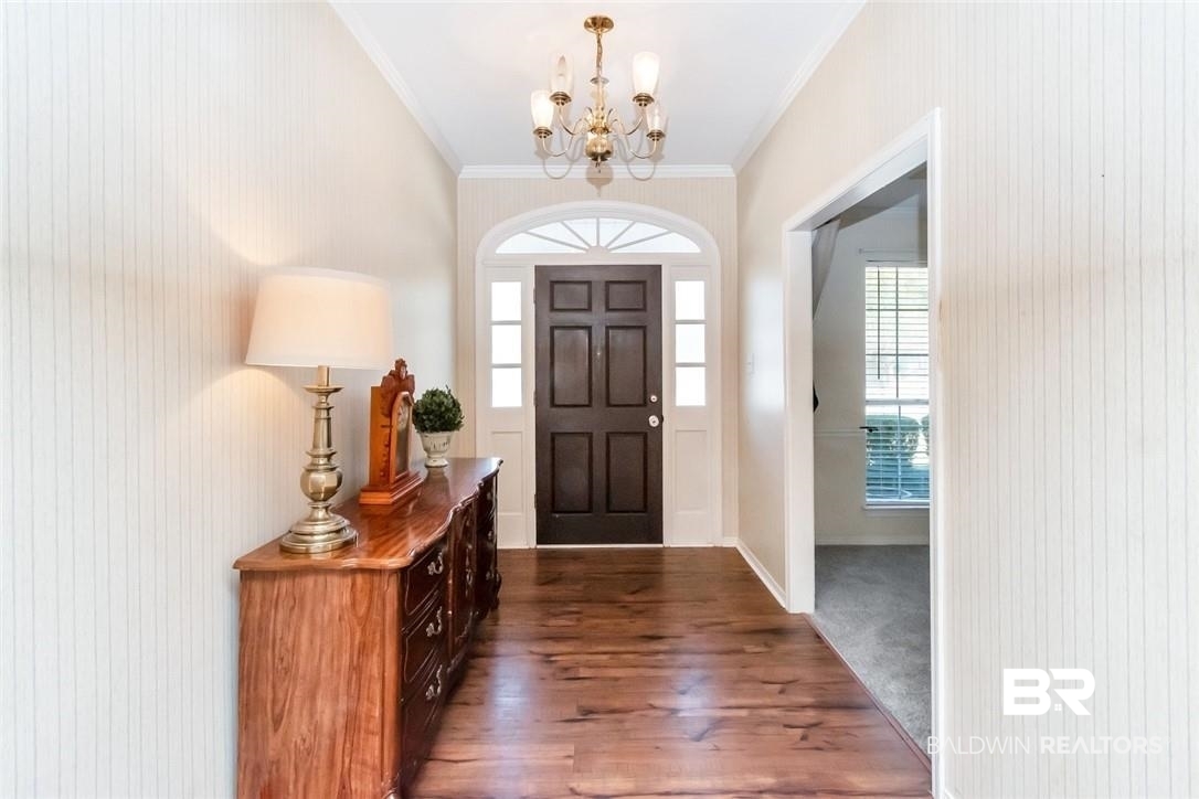 6601 Conde Court Mobile, AL 36695 - Photo 4 of 30 Foyer entrance with dark wood-type flooring, crown molding, and a notable chandelier