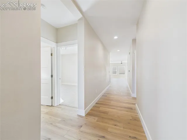 a view of a hallway with wooden floor and a bathroom