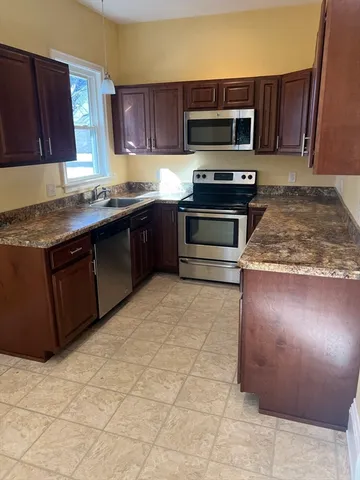 a kitchen with stainless steel appliances granite countertop a stove a sink and a microwave