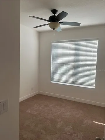 an empty room with a ceiling fan and window