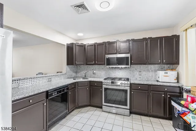 a kitchen with stainless steel appliances granite countertop a sink stove top oven and cabinets
