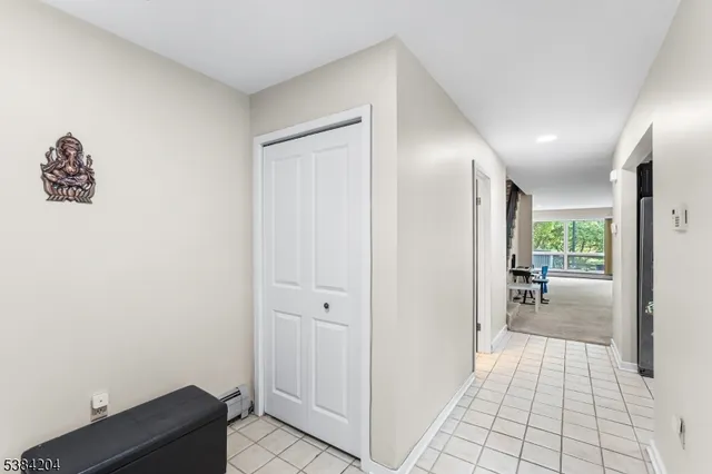 a view of a hallway to a livingroom with wooden floor and a cabinet