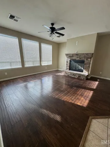 a view of an empty room with wooden floor fireplace and a window