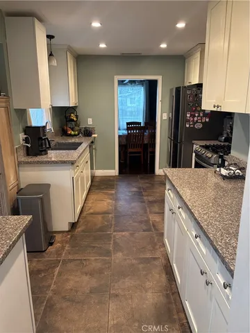 a large kitchen with stainless steel appliances granite countertop a stove a sink and a refrigerator