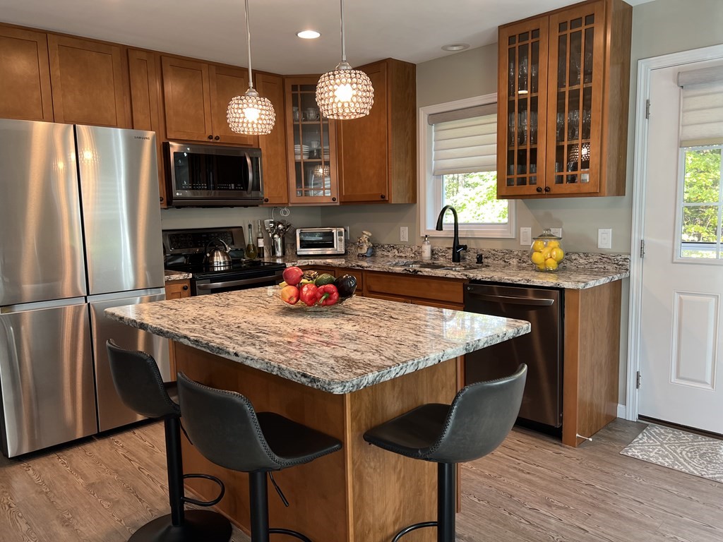 171 Forest Street Middleton, MA 01949 - Photo 9 of 35 a kitchen with granite countertop kitchen island stainless steel appliances a sink and a refrigerator