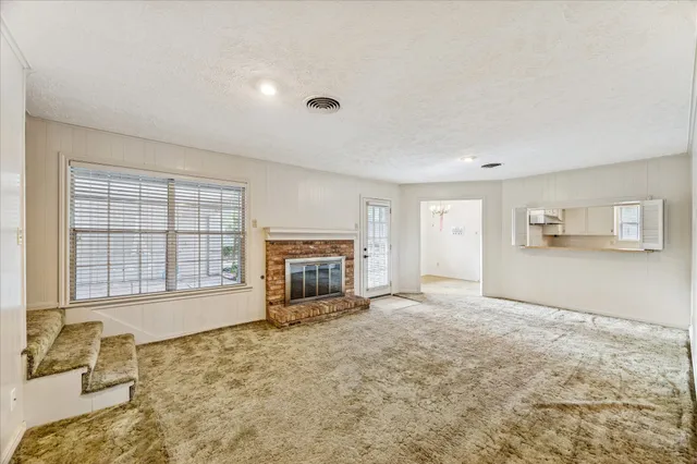 a view of an empty room with a fireplace and a window