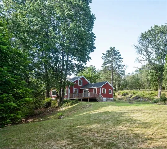 a house view with a big yard plants and large trees