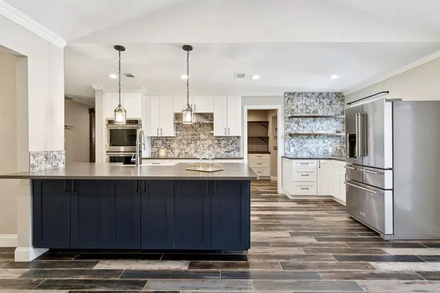 a kitchen with stainless steel appliances granite countertop a refrigerator a oven and a wooden floors