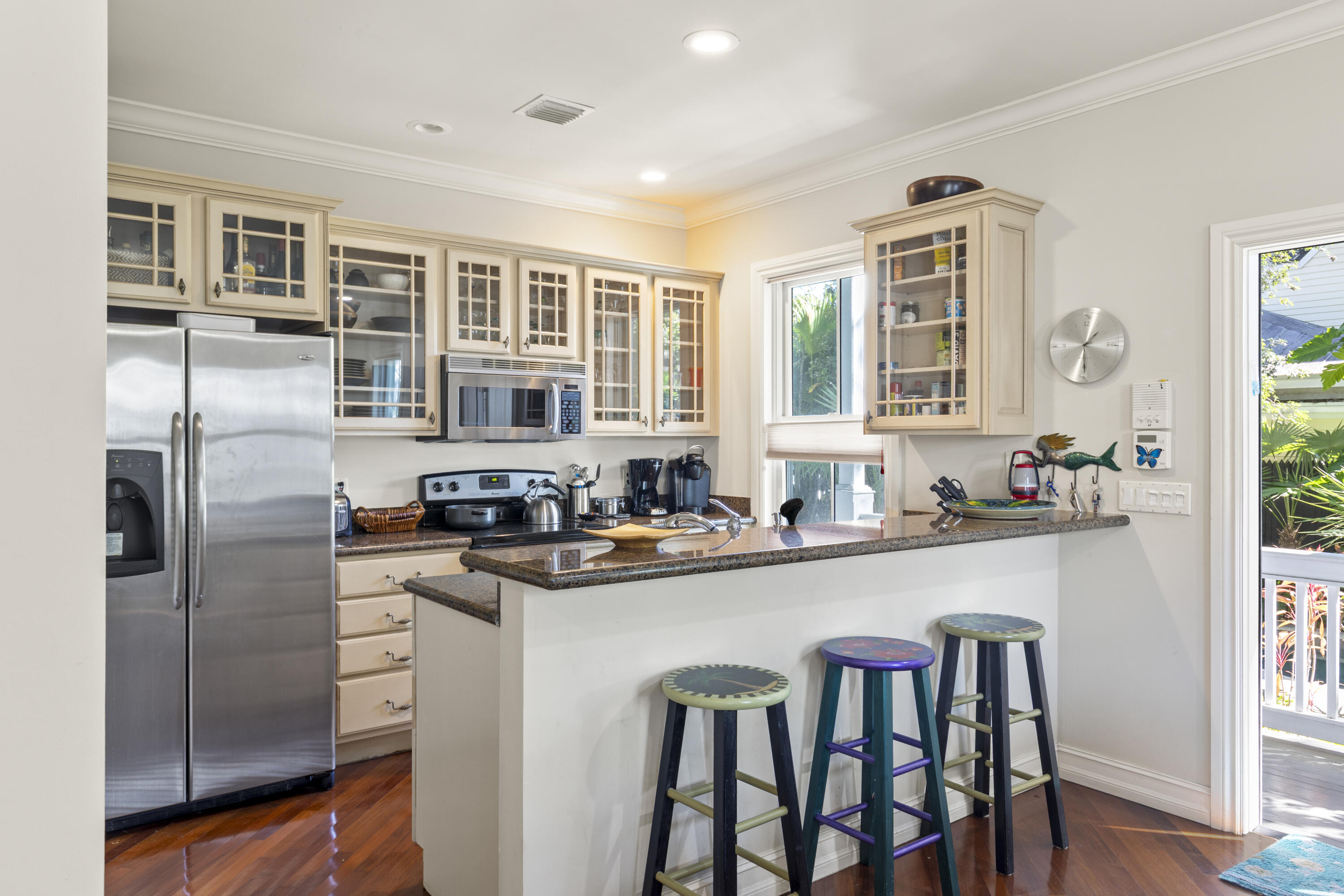 120 Angela Street, Unit 102 Key West, FL 33040 - Photo 7 of 24 a kitchen with stainless steel appliances granite countertop a refrigerator a stove a sink dishwasher a dining table and chairs with wooden floor