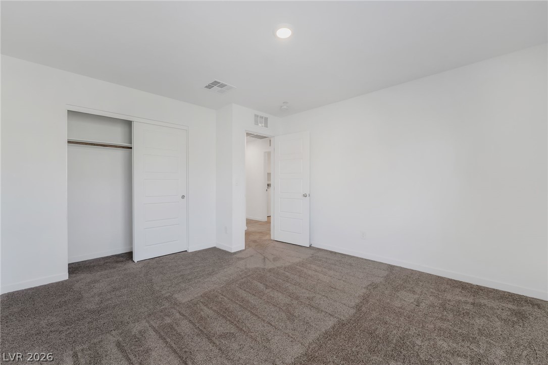 894 Cadence View Way Henderson, NV 89011 - Photo 21 of 23 A spacious bedroom features plush carpeting and convenient closet access, perfect for serene living.
