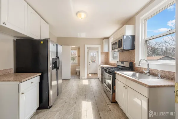 a kitchen with stainless steel appliances granite countertop a refrigerator a sink dishwasher a stove with white cabinets and wooden floor