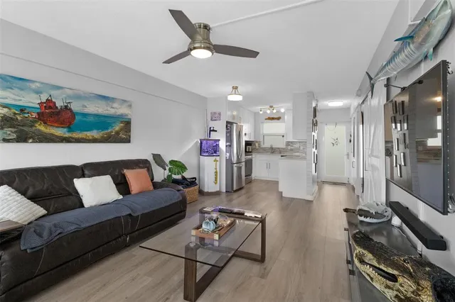 a living room with furniture and a flat screen tv with kitchen view