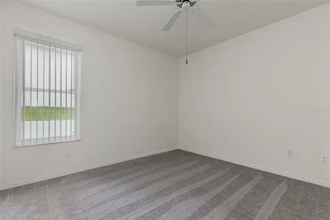an empty room with a ceiling fan and carpet
