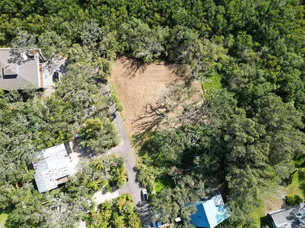 an aerial view of residential house with outdoor space and trees all around