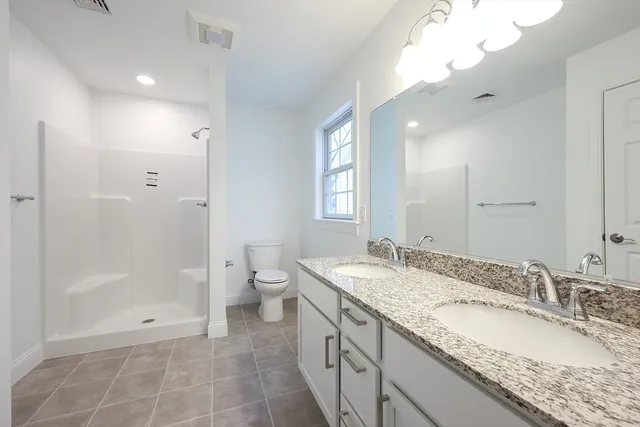 a spacious bathroom with a granite countertop sink a toilet and shower