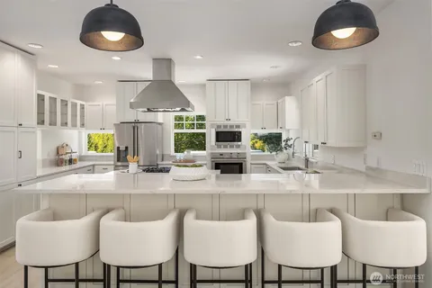 a kitchen with stainless steel appliances granite countertop a kitchen island and chairs in it