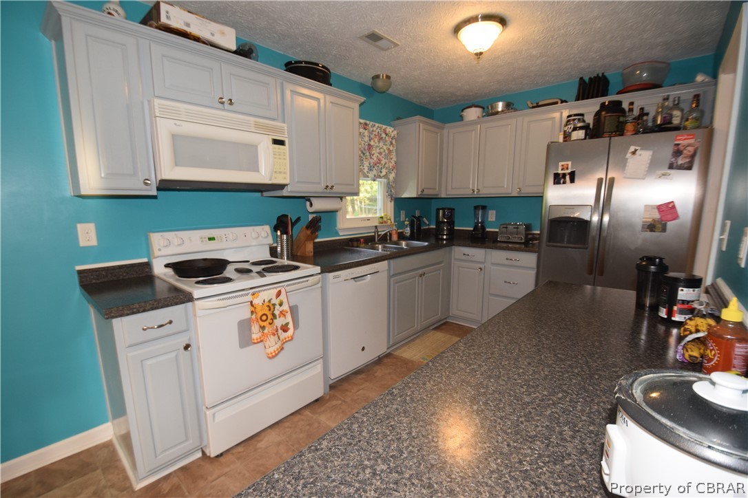 561 Possum Point Road Port Haywood, VA 23138 - Photo 13 of 23 a kitchen with stainless steel appliances granite countertop a sink stove and cabinets