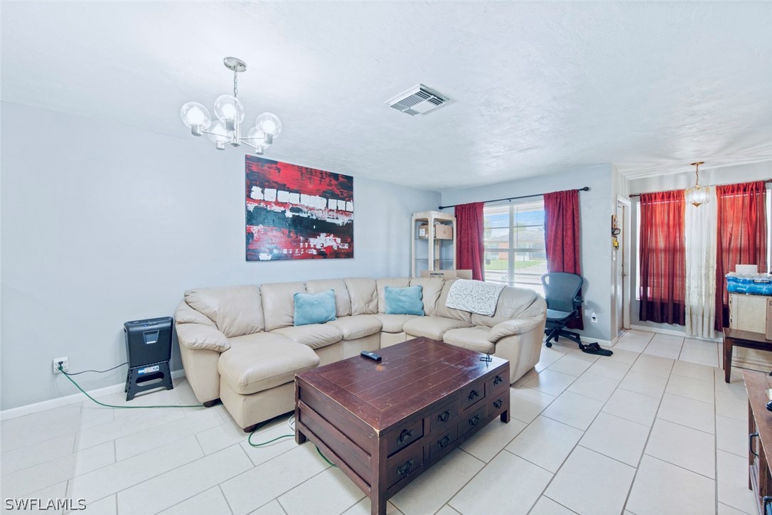 1604 Ridgecrest Street Lehigh Acres, FL 33936 - Photo 12 of 26 a living room with furniture a rug and a chandelier