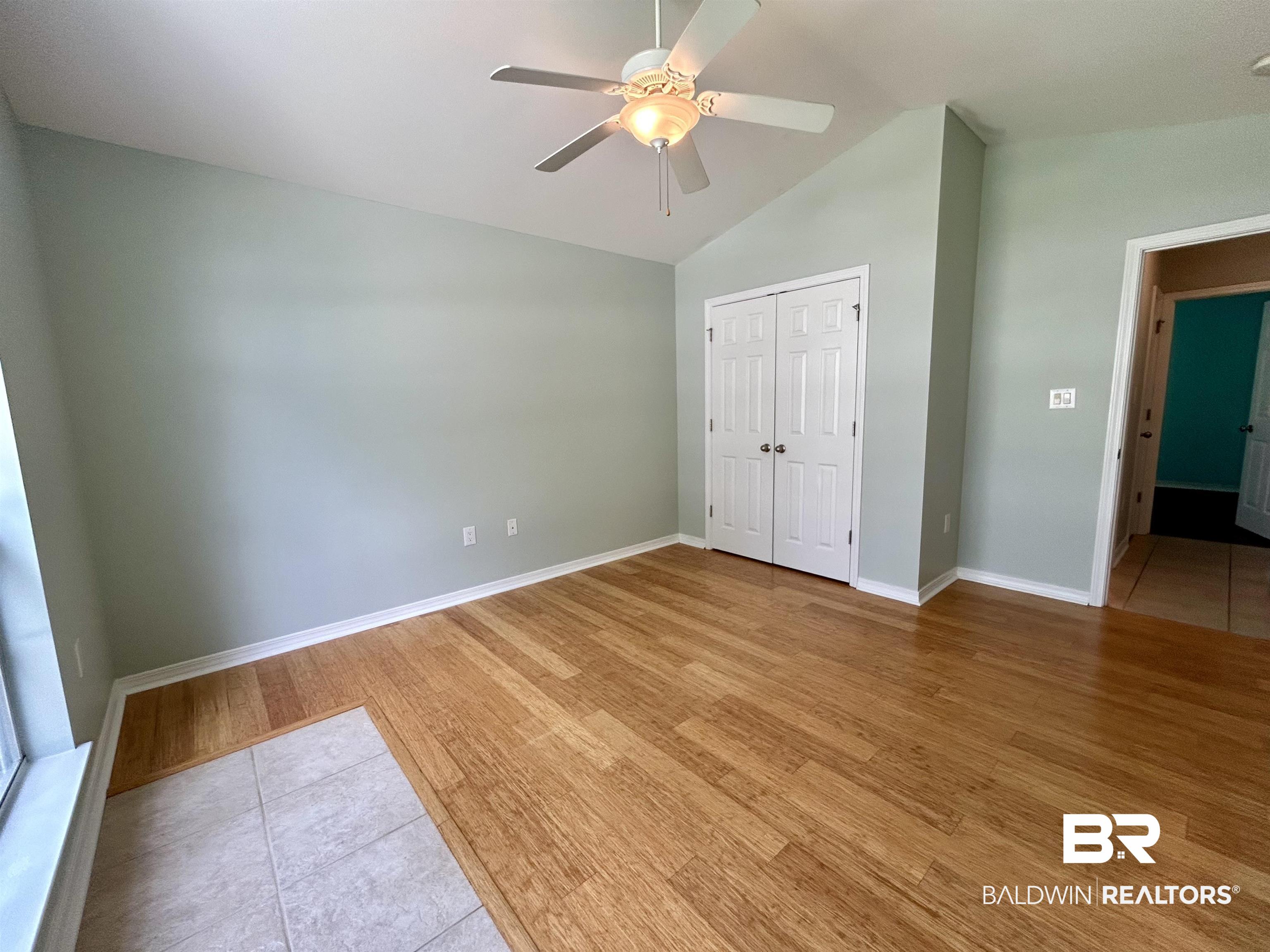 7198 Raintree Lane Gulf Shores, AL 36542 - Photo 20 of 33 Vaulted ceiling room featuring wood-finish flooring, a ceiling fan with light fixture, and bifold closet doors