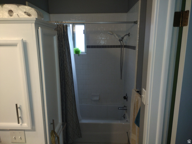 157 West 500 South Logan, UT 84321 - Photo 33 of 38 Bathtub and shower combination featuring white subway tile surround with a dark accent band, a showerhead with a handheld sprayer, and an integrated window