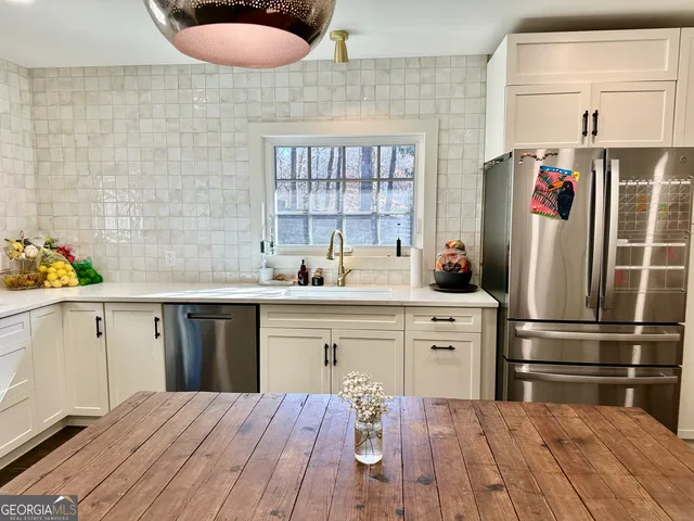 a kitchen with stainless steel appliances a dining table chairs refrigerator and a sink