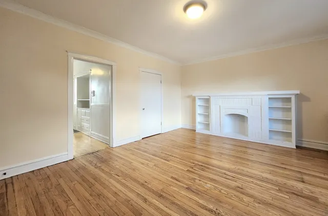 a view of empty room with wooden floor and fireplace
